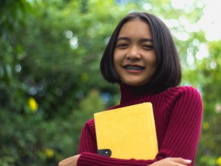 Young asian girl reading notebook at the green garden.