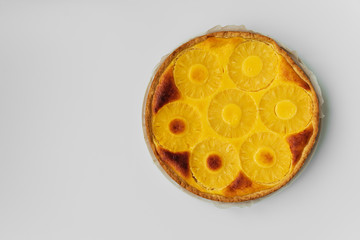 Upside down pineapple cake on white table. Summer tropical dessert. Top view. Copy space