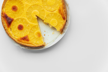 Sliced upside down pineapple cake on white table. Summer tropical dessert. Top view. Copy space