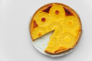 Sliced upside down pineapple cake on white table. Summer tropical dessert. Top view. Copy space