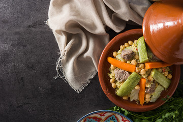 Traditional tajine with vegetables, chickpeas, meat and couscous on black slate. Copyspace