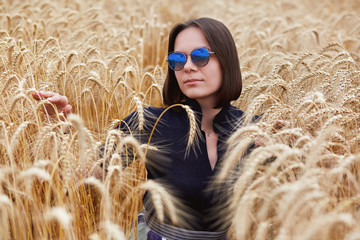 Portrait of beautiful young woman in glasses in wheat field