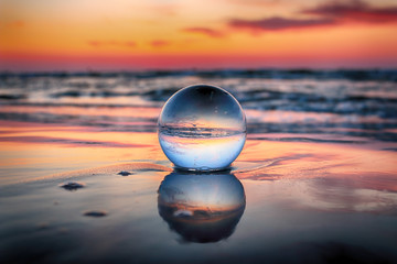 Beautiful sunset on the beach in Slowinski National Park near Leba, Poland. View of a starfish through a glass, crystal ball (lensball) for refraction photography. Wild, untouched nature. - obrazy, fototapety, plakaty