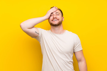 Handsome man over yellow background laughing