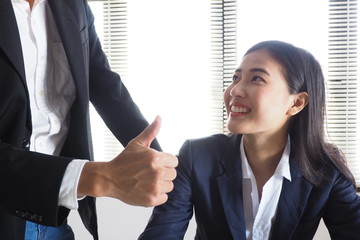 Boss giving thumbs up to his female colleague after work done reaching the assigned sales target to...