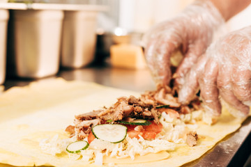 partial view of cook in gloves preparing doner kebab