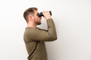 Handsome man over isolated white wall with black binoculars