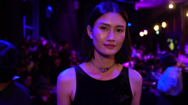 Beautiful Asian woman walking through a nightclub - slow motion