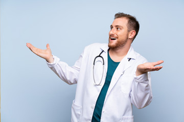 Handsome doctor man over blue wall with surprise facial expression