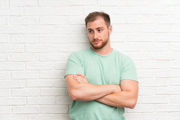 Blonde man over brick wall thinking an idea