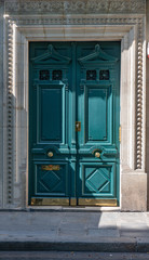 Old wooden door. Aquamarine color door of old building with golden shiny doorknobs and details. Vintage ornate wooden door painted in sea-green color. Elegant entrance of retro house in Paris France.