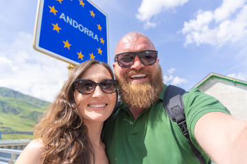 Happy smiling couple traveler making selfie with Andorra European Country road sign - tourism and freedom concept
