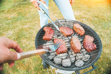 POV picture of people making meat barbecue - couple cooking dinner outdoor - bbq party on backyard...