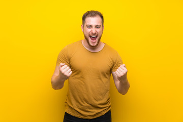 Blonde man over isolated yellow wall frustrated by a bad situation