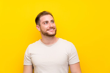 Fototapeta premium Handsome man over yellow background laughing and looking up