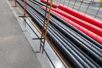 Black and red PVC pipes for underground cables and structures at a construction site on a city...
