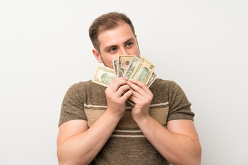 Handsome man over isolated white wall taking a lot of money