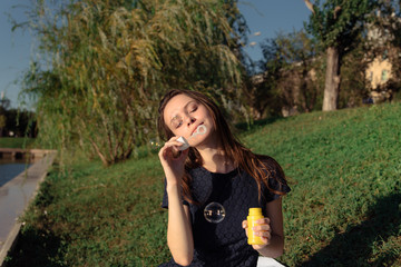 happy beautiful woman blowing soap bubbles outdoor