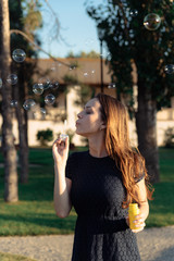 happy beautiful woman blowing soap bubbles outdoor