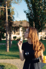 happy beautiful woman blowing soap bubbles outdoor