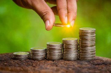 A hand putting money coins stack for save money concept. Money management is growing a business.