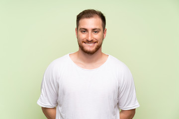 Handsome man over green background having doubts and with confuse face expression