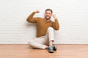 Blonde man sitting on the floor celebrating a victory