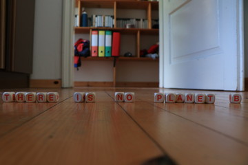 Wooden orange and white letters dice forming the slogan 'THERE IS NO PLANET B' on wood background. Sentences against global warming, banner