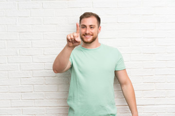 Blonde man over brick wall touching on transparent screen