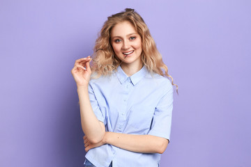 romantic beautiful smiling woman holding glasses near her mouth. thinking about her boyfriend, woman fells in love. isolated blue background, lifestyle, optimism