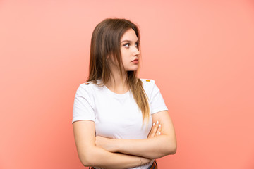 Teenager girl over isolated pink wall looking side