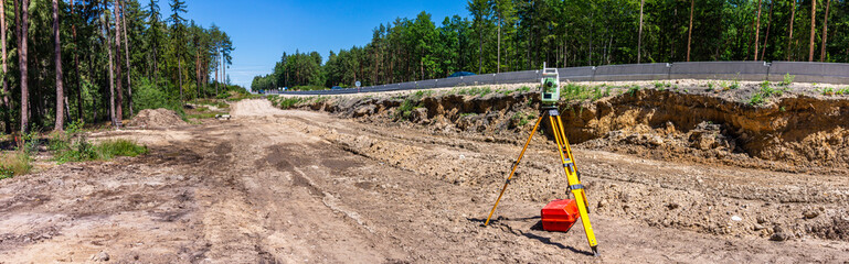 Fototapeta na wymiar Panoramic view of surveyor equipment (theodolite or total positioning station) on the construction site of the motorway, highway or road