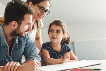 Father and mother teach daughter to draw.They sitting in living room.Education and family concept.