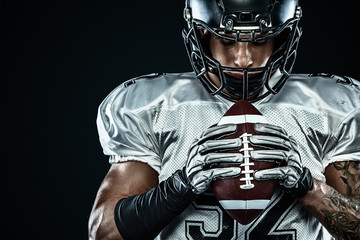 American football sportsman player in helmet isolated run in action on black background. Sport and...