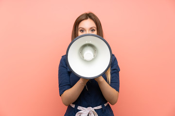 Teenager girl over isolated pink background shouting through a megaphone