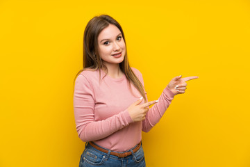 Teenager girl over isolated yellow background pointing finger to the side