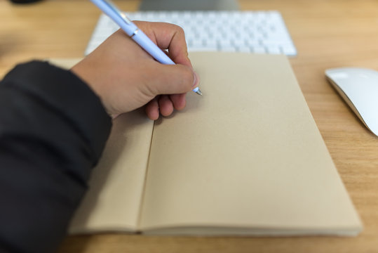 Hombre escribiendo cuaderno, libro con esfero blanco
