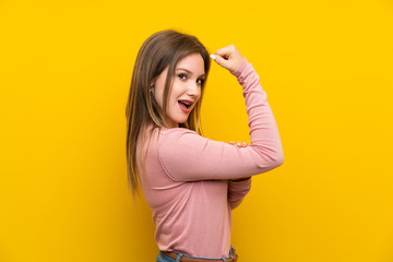 Fototapeta premium Teenager girl over isolated yellow background making strong gesture