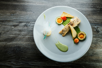 top view on baked white fish piece decorated with garnish