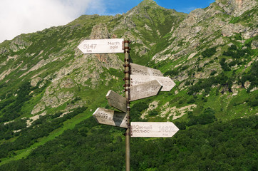 Road sign with mount names and destination in Russian and English on wooden boards