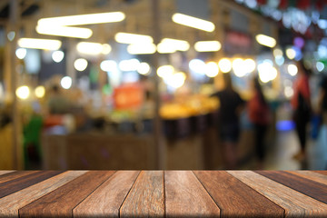 Wooden table of brown in front blurred night street market background, use for presentation and background template, product advertising
