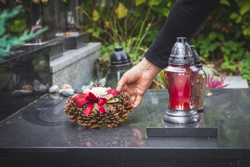 Widower is putting wreath on tombstone at cemetery. Sad memories for dead person at All Souls Day