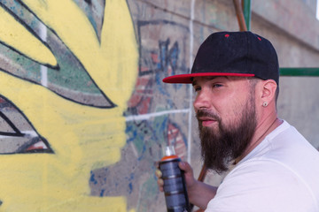 Graffiti artist painting with aerosol spray bottle