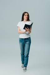 beautiful girl in white t-shirt and jeans reading book isolated on grey