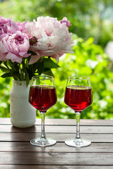 Glass of red wine,  bouquet of flowers on  garden background