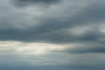 Dark stormy sky with sunlight shining through. Long exposure shot.