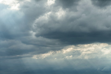 Dark stormy sky with sunlight shining through.