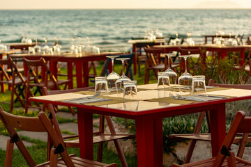 Tables in outdoor cafe or restaurant served for dinner on beach with sea view
