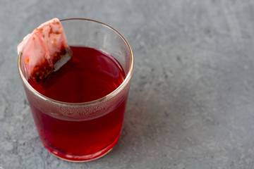Red hibiscus (karkade, rose) teabag in a glass
