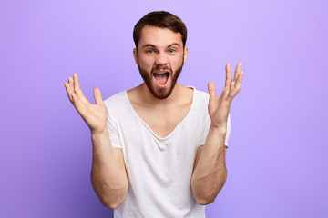 funny man with raised hands shouting at somebody, screaming. man singing a song, isolated blue background. studio shot